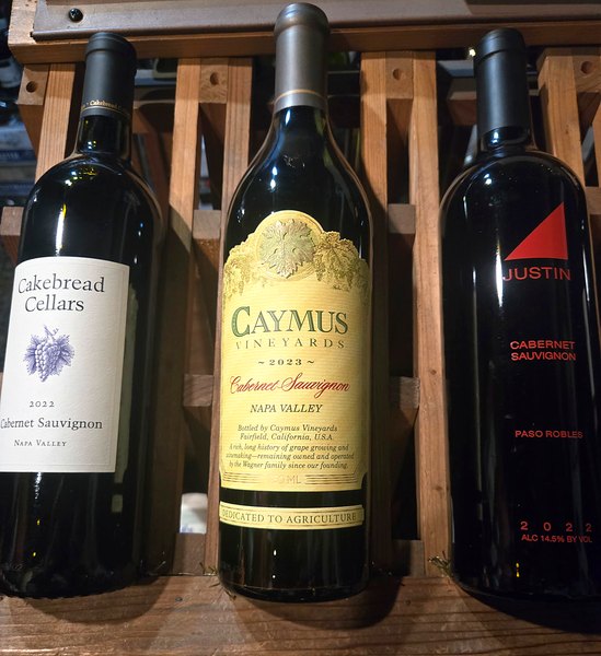 California Cabernet bottles including Cakebread, Caymus, and Justin on a wine shelf
